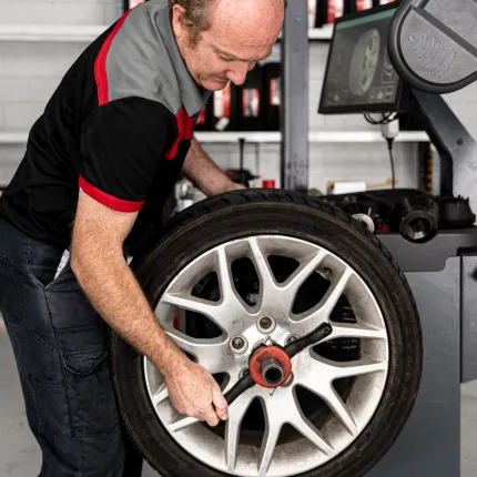 Professional mechanic performing wheel alignment service on European car tyre at Brisbane workshop