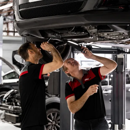 Two mechanics servicing European car undercarriage at Brisbane automotive workshop