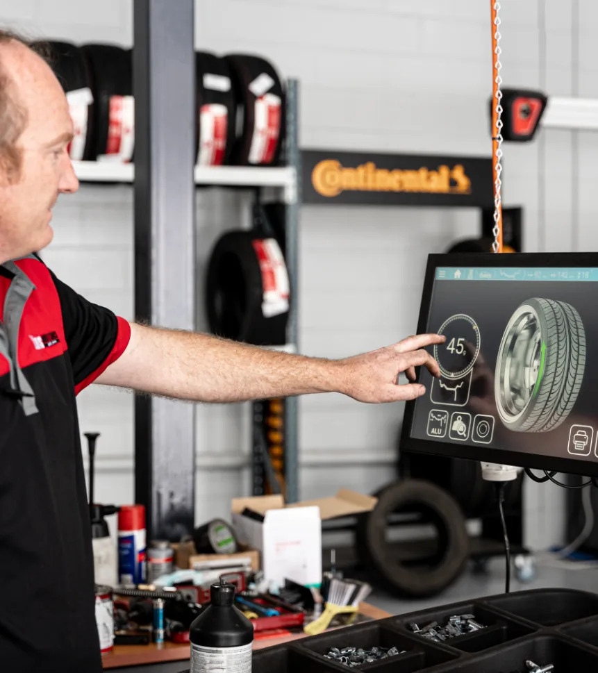 Mechanic using digital wheel alignment system at European car service workshop