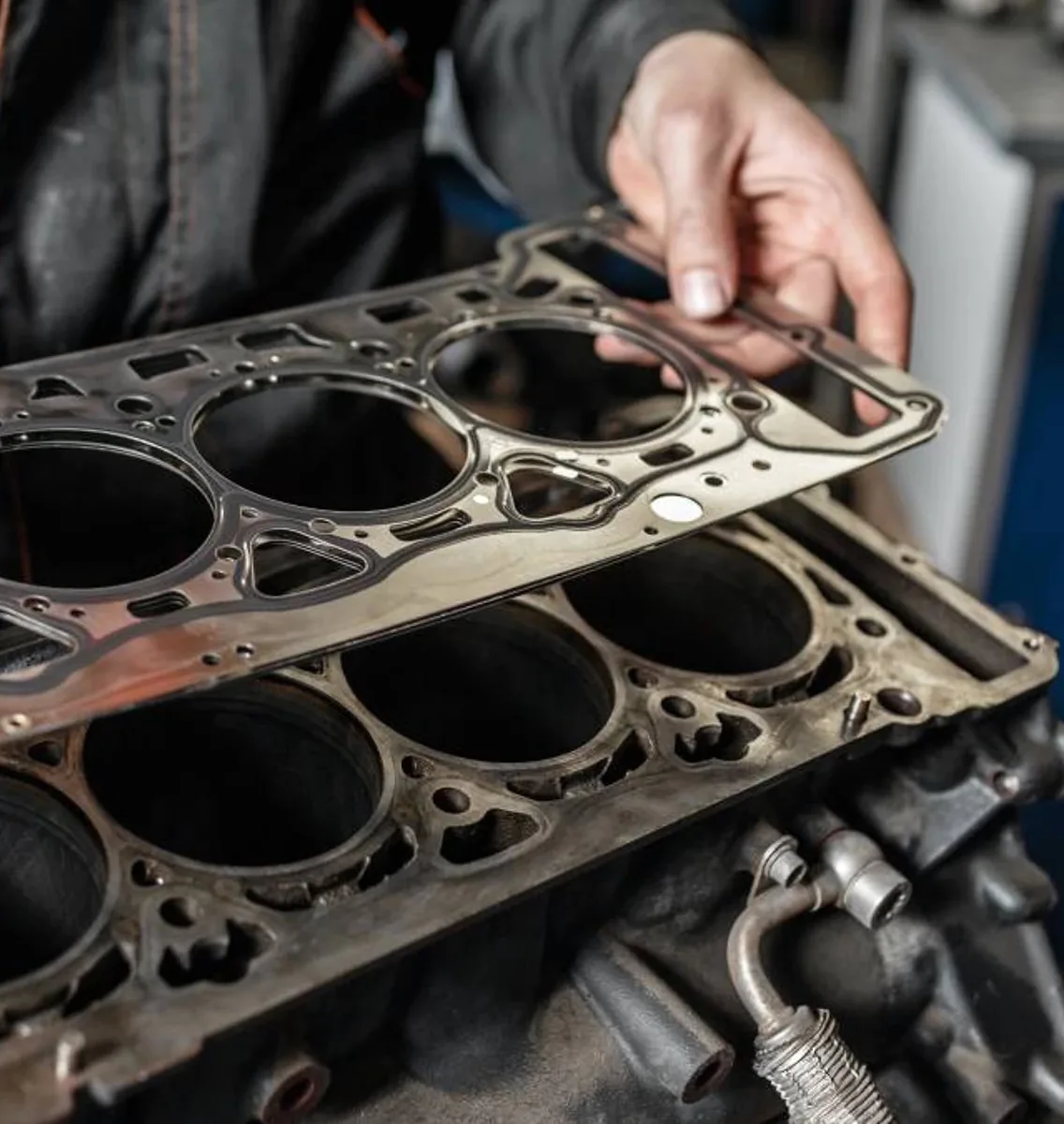 Mechanic examining blown head gasket from European luxury car engine