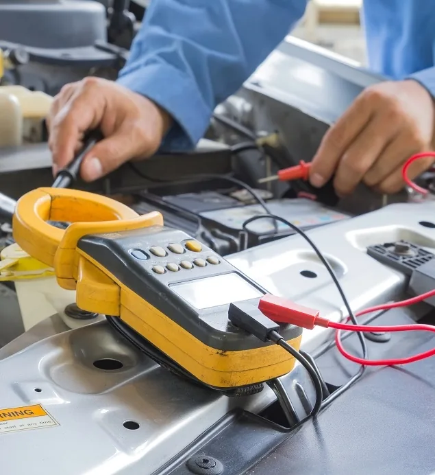 Auto electrician testing European car battery with digital multimeter at Brisbane workshop
