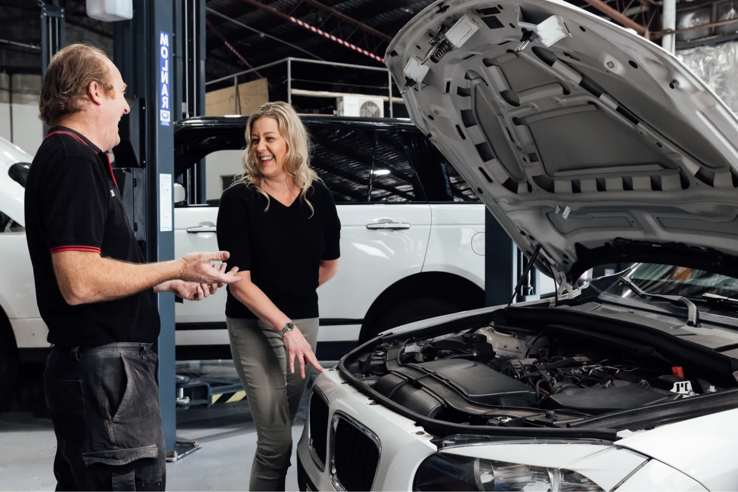 Mechanic explaining European car service to female customer at Brisbane workshop