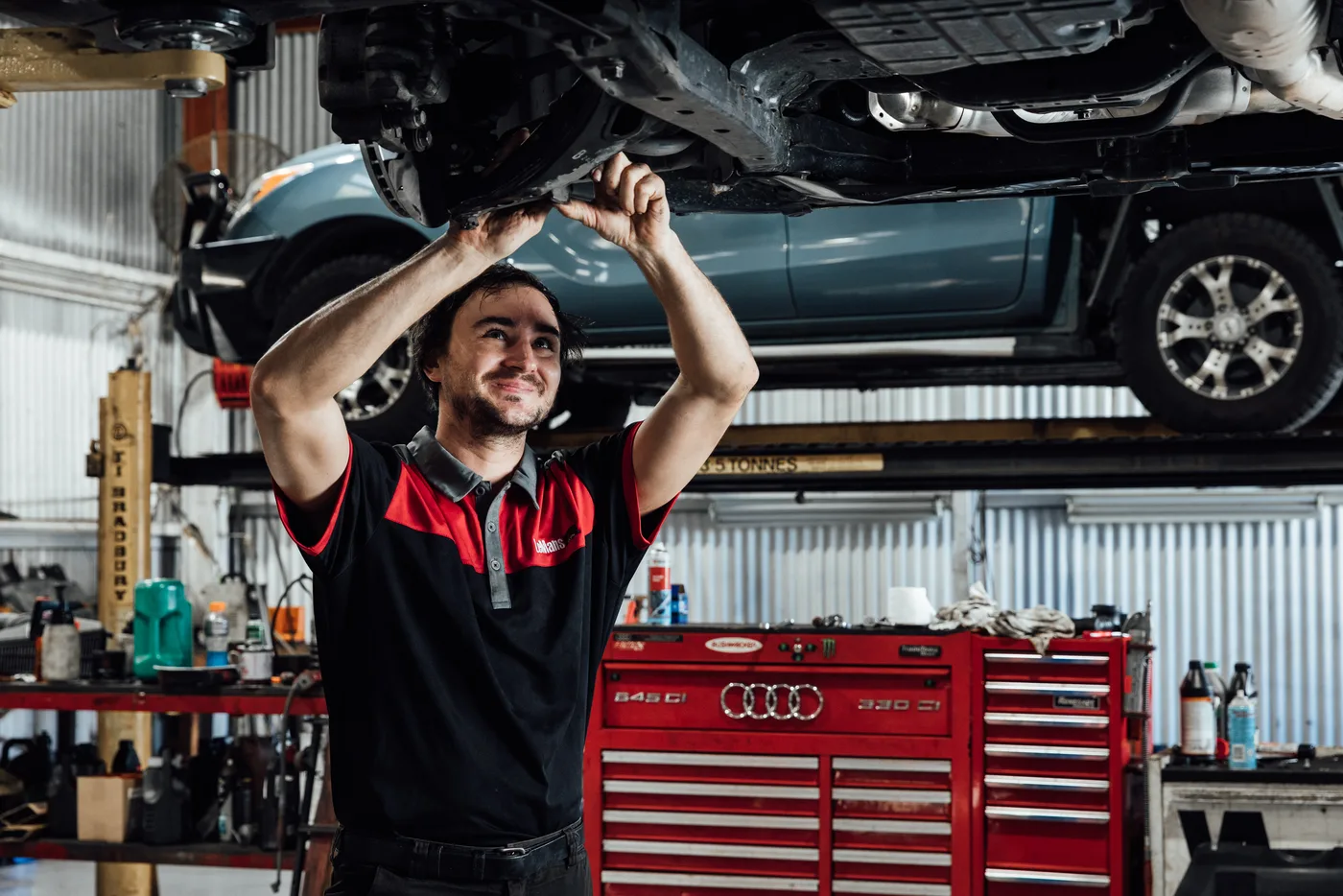 Bosch Service Brisbane mechanic working under a hoisted vehicle during a brake replacement